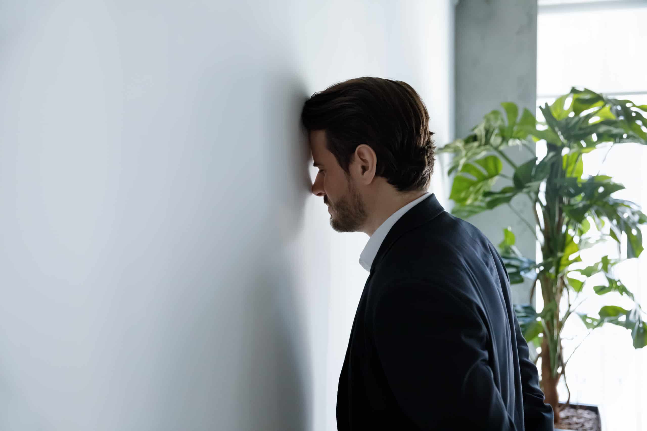 Man leaning against wall showing stress, coping with mental health challenges.