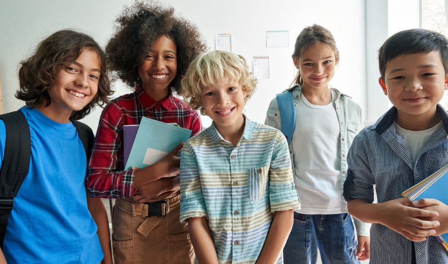 Group of happy diverse children smiling in classroom setting.