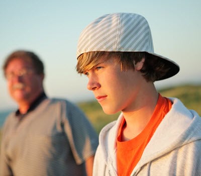 Teen boy outdoors during therapy session with adult, focusing on mental health support.