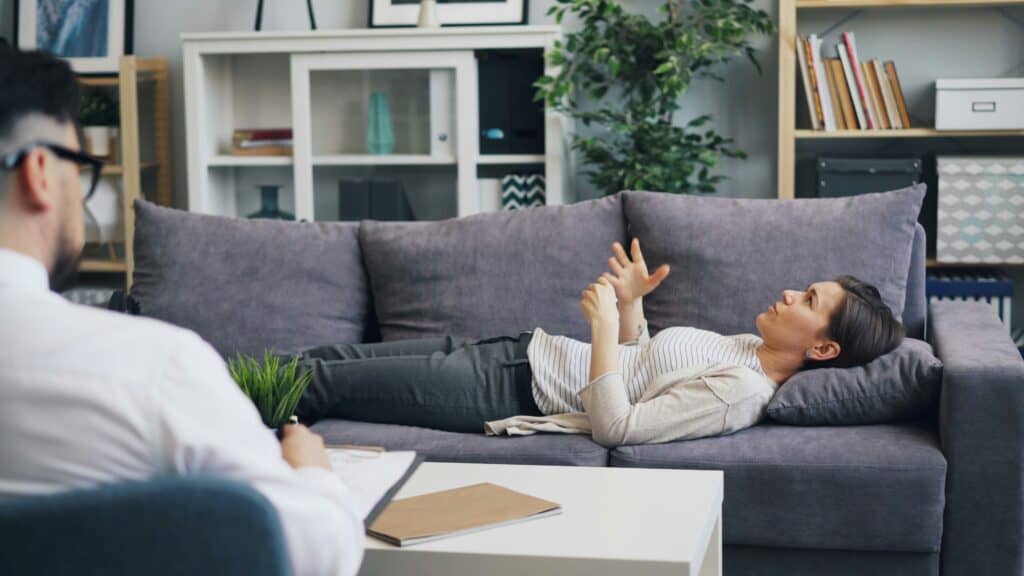 EMDR therapy session with a client lying on a sofa, engaging in trauma processing.